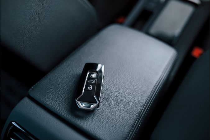 A Keyless car key placed on a car armrest starting the ignition using signals